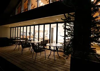 夜のthirty nine cafeのテラス席の様子。ウッドデッキの上に丸テーブルと椅子がゆったりと配置されています